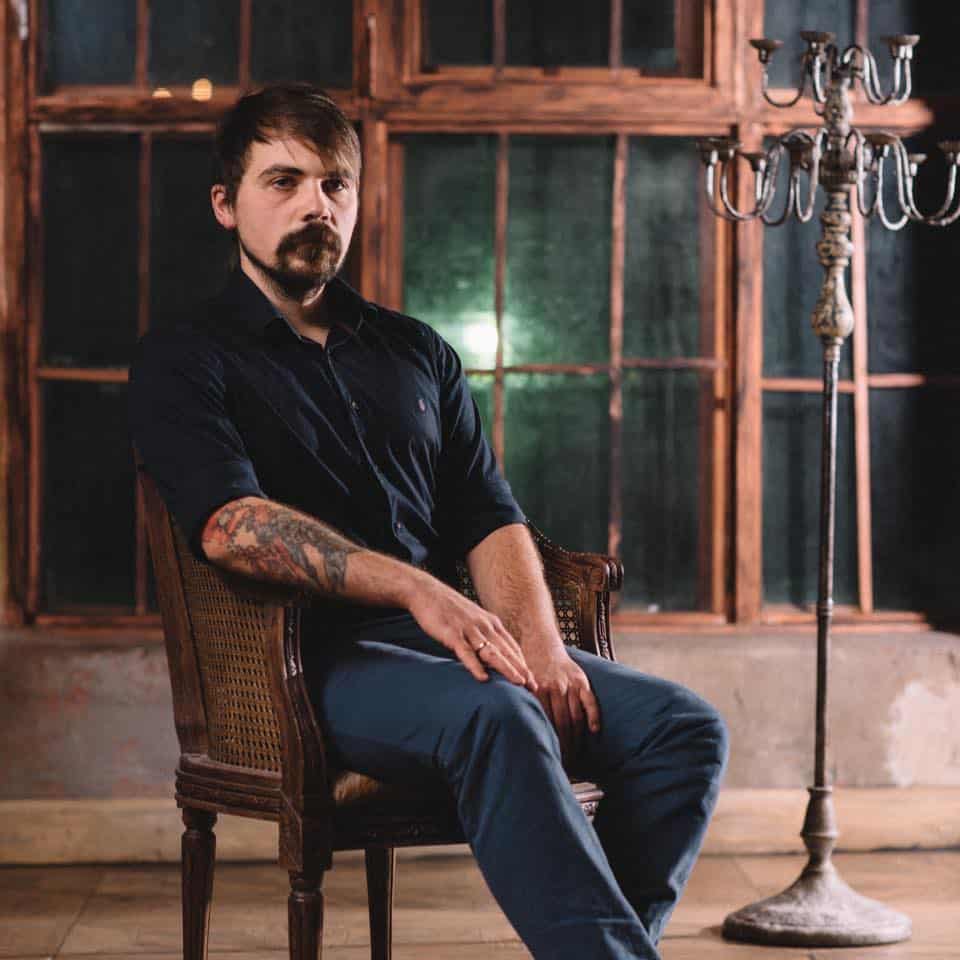 Dima Sergeev, guest tattoo artiest die poseert op een stoel