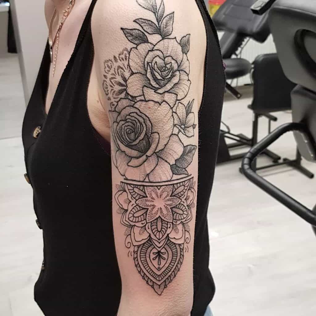 black and grey lijnwerk tattoo op bovenarm met bloem en mandala elementen. Gezet bij Inksane tattoo en piercing